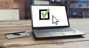 Notebook exibindo um símbolo de check verde na tela, simbolizando tarefas concluídas e metas financeiras atingidas com planejamento.