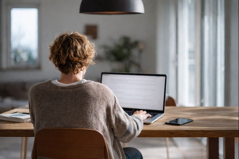 Pessoa trabalhando no notebook em casa criando conteúdo para ganhar dinheiro online sem aparecer